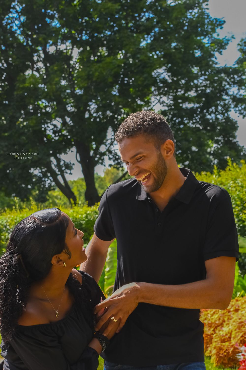 A loving couple shares a tender moment in a vibrant garden with colorful flowers.