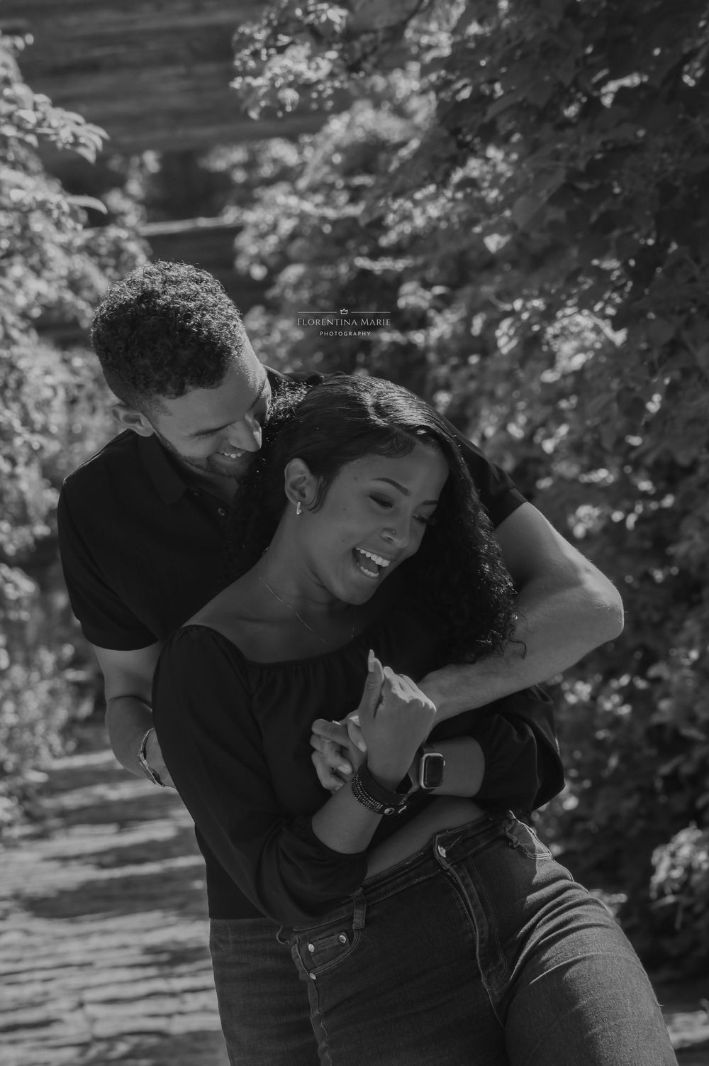 A playful moment between a couple sharing laughter on a garden walkway.