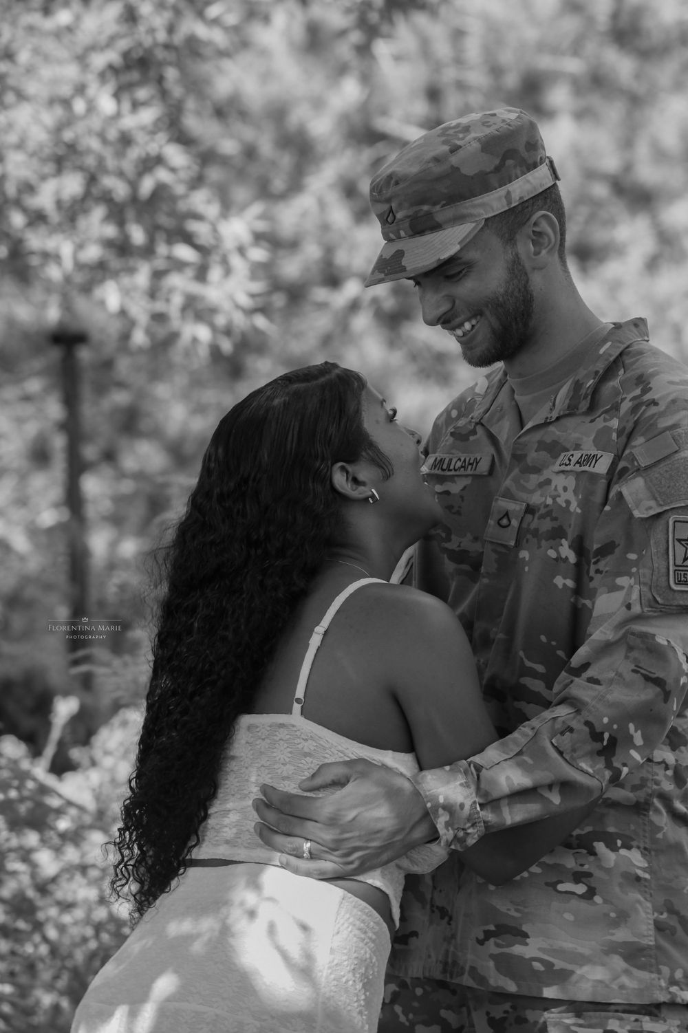 A tender moment between a couple as they embrace outdoors surrounded by blooming trees.