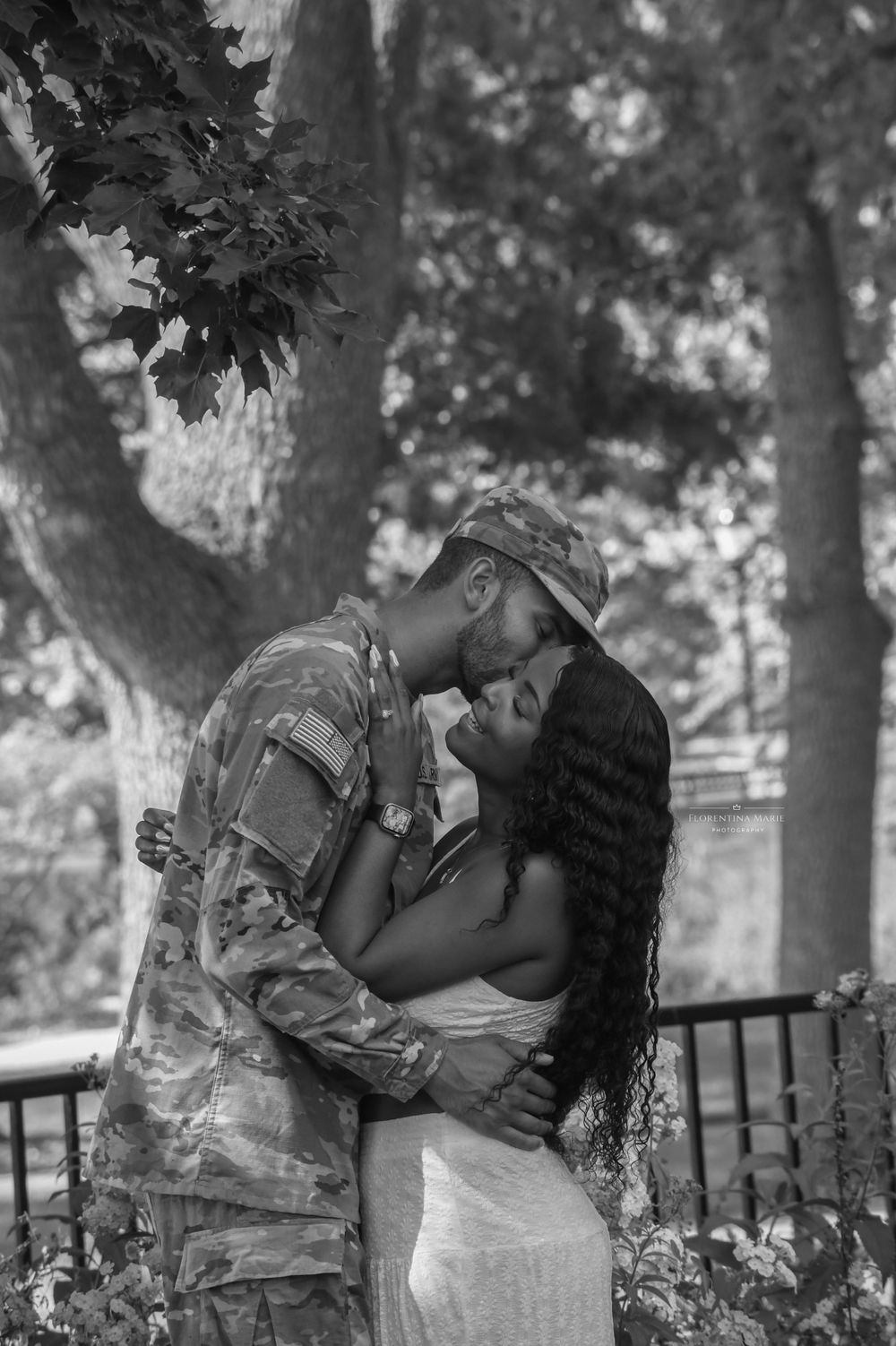 An intimate black and white portrait of a couple sharing a tender moment in a park setting.