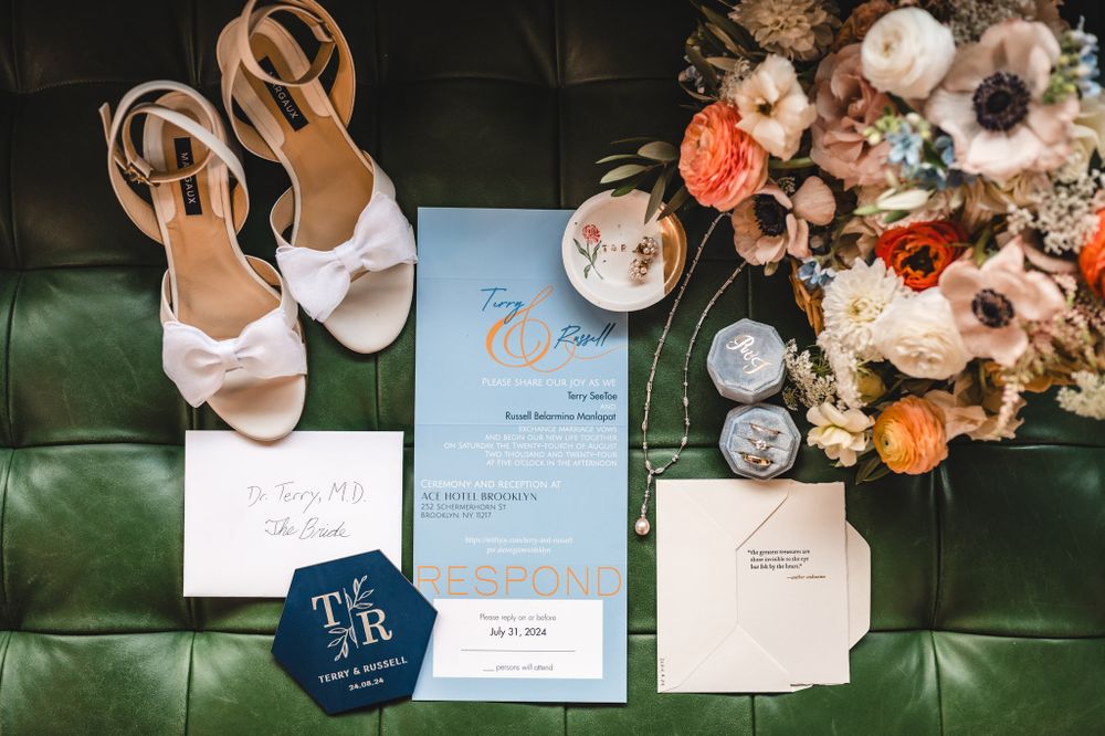 Wedding stationery and floral details arranged on dark green leather surface.