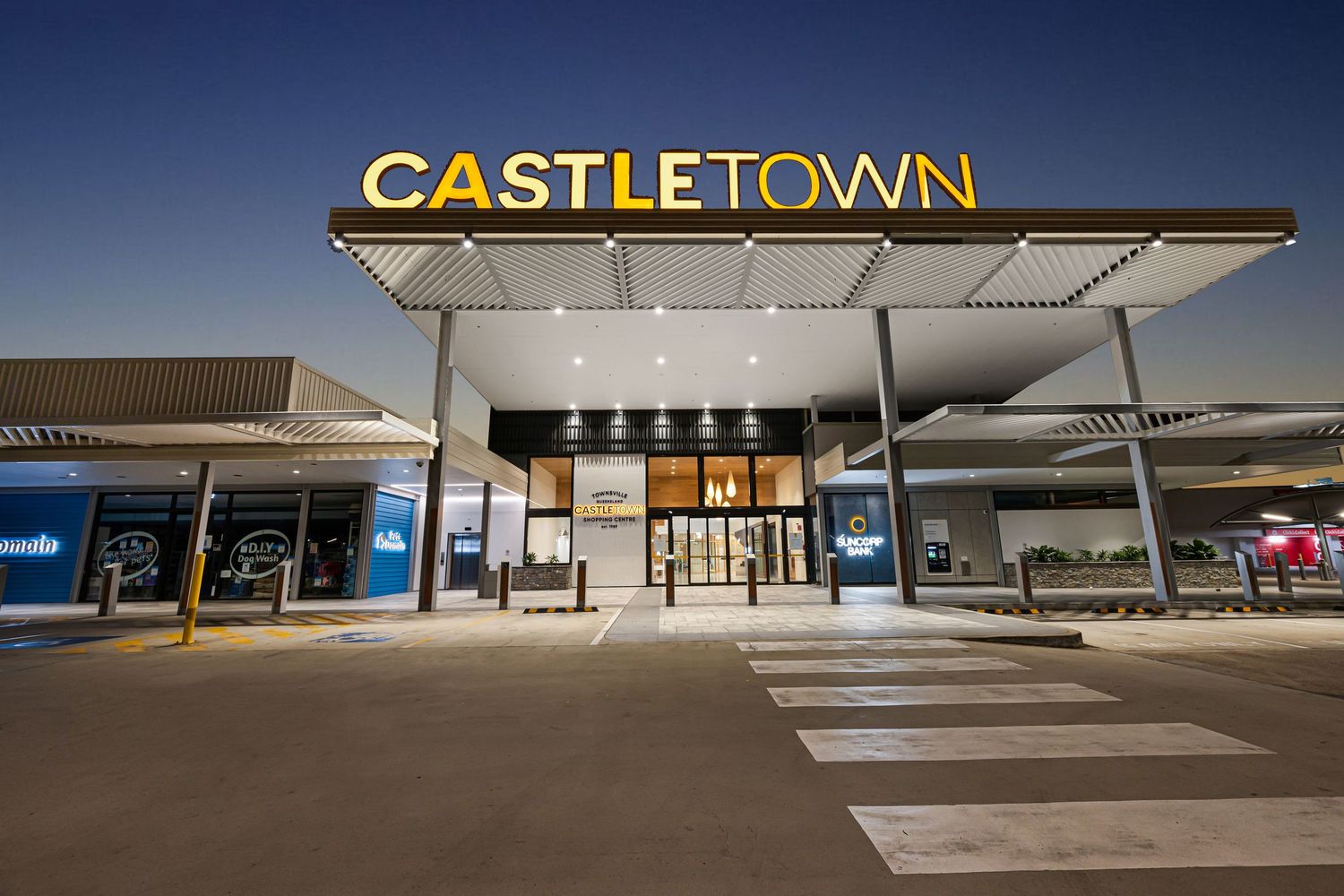 Empty shopping center exterior with Castletown signage illuminated at night.