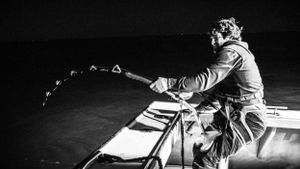 Dramatic black and white shot of someone casting a fishing rod at night.