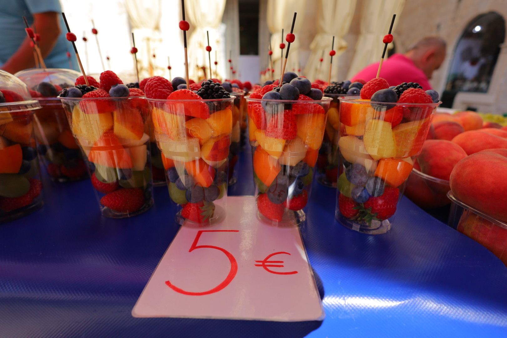Colorful fruit cups priced at 5 euros displayed on purple surface.
