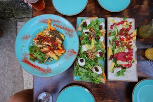 Colorful Mediterranean dishes served on turquoise plates with fresh salads and garnishes.