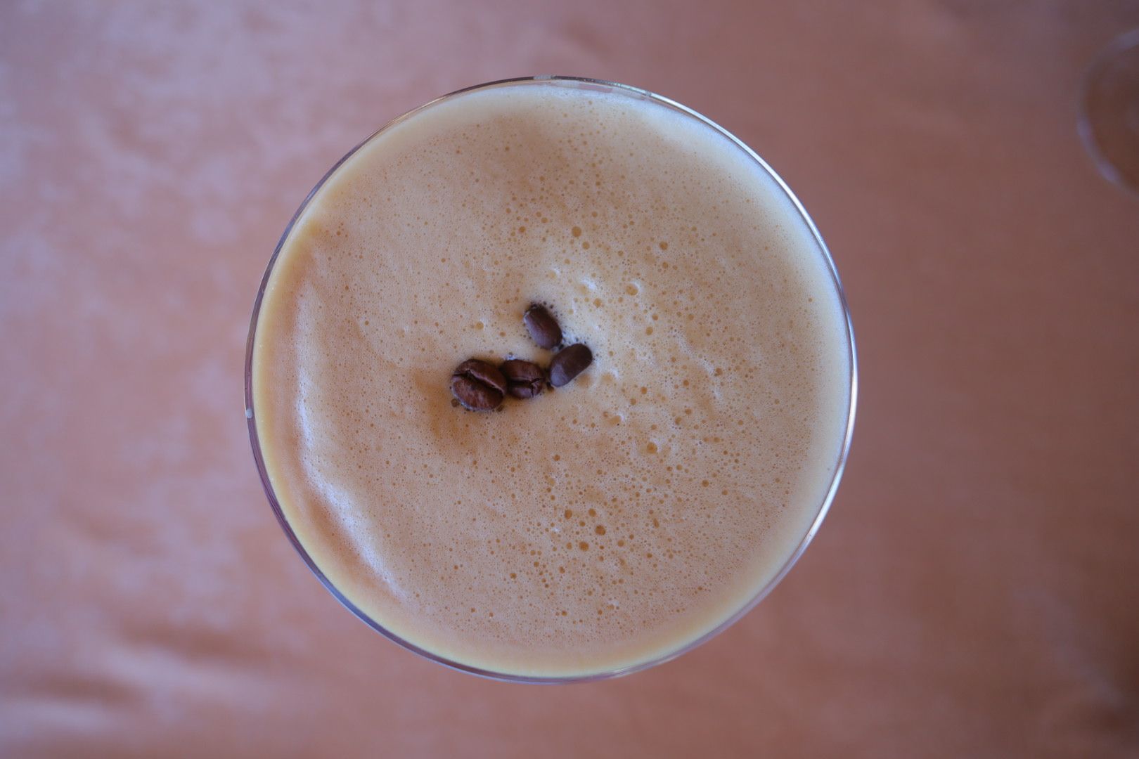 Creamy espresso martini with coffee beans garnish viewed from above.