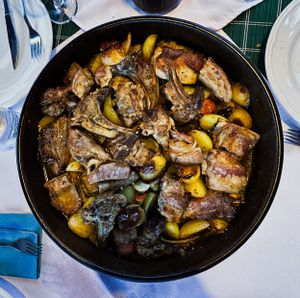 Skillet filled with roasted meat and vegetables in a rustic presentation.