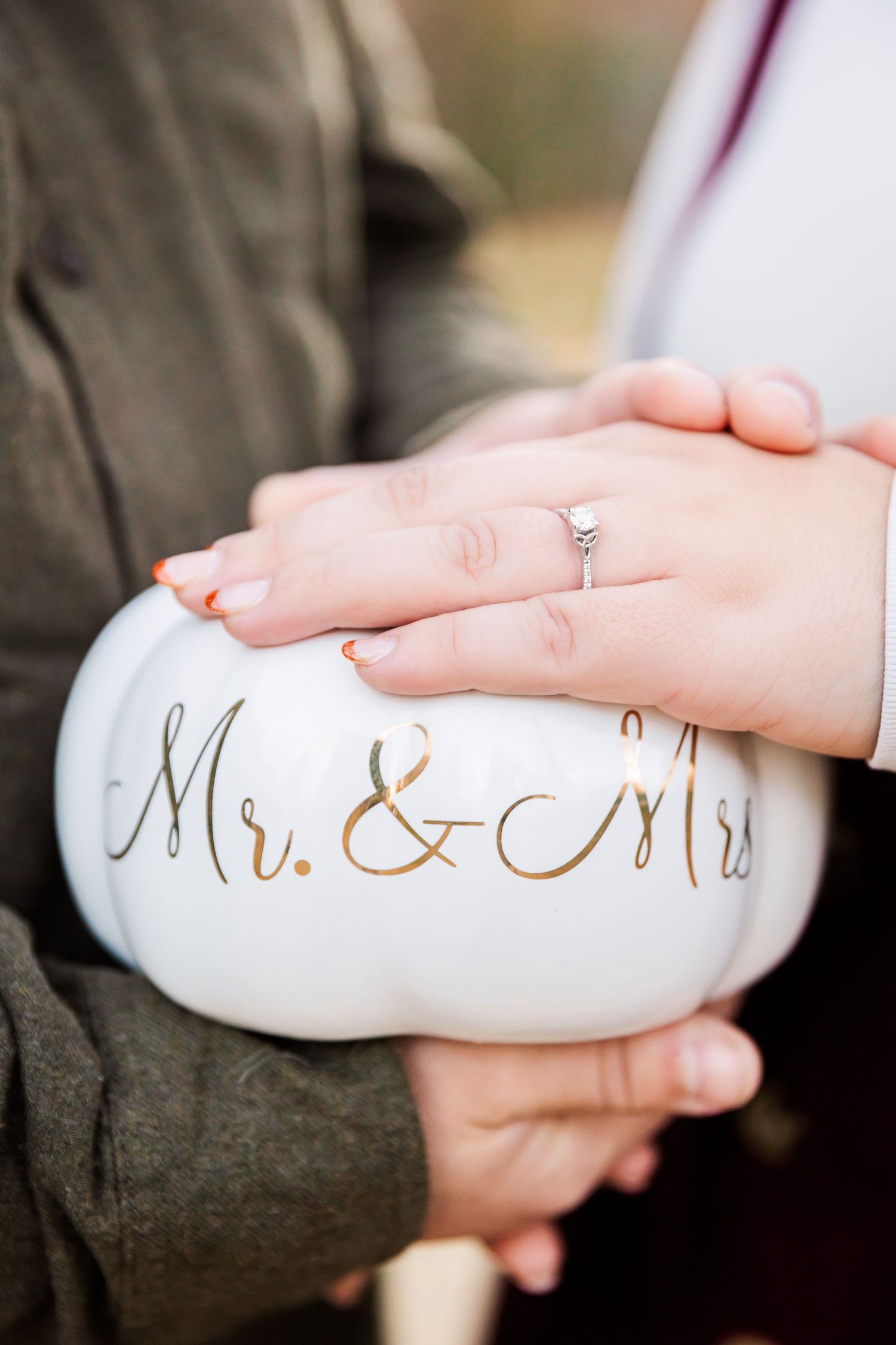 Close up of engagement ring on white decorative pumpkin with Mr. & Mrs. text.