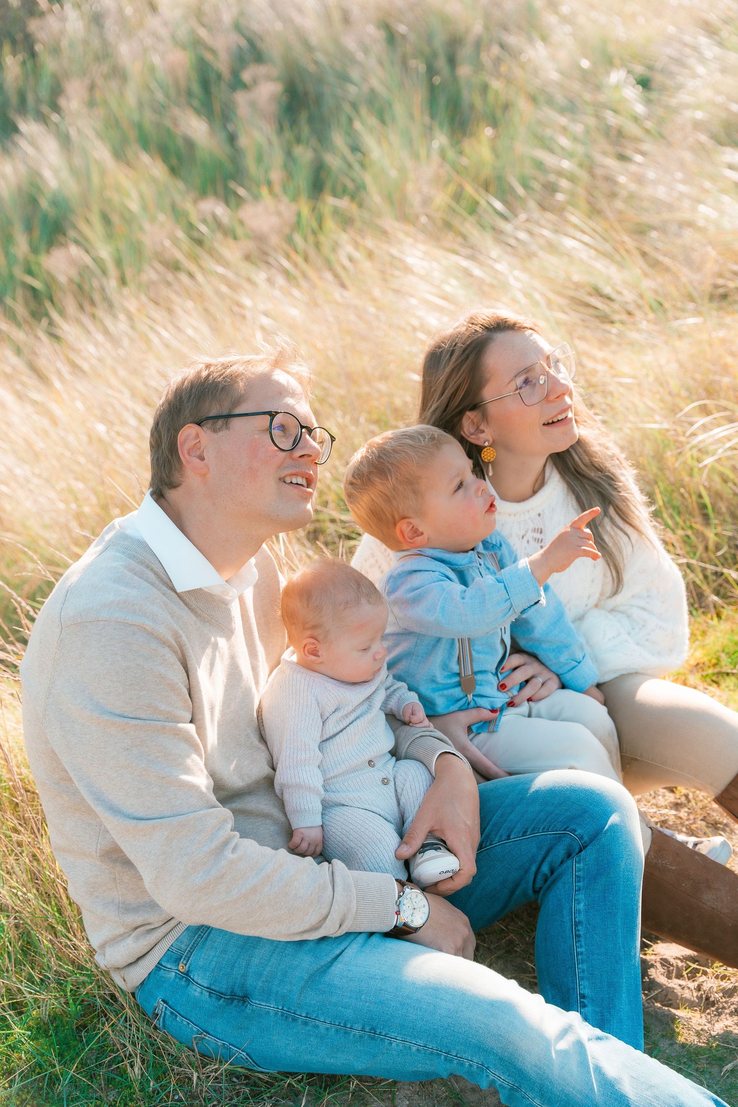 A heartwarming family moment in a sunlit meadow with tall golden grass swaying in the breeze.