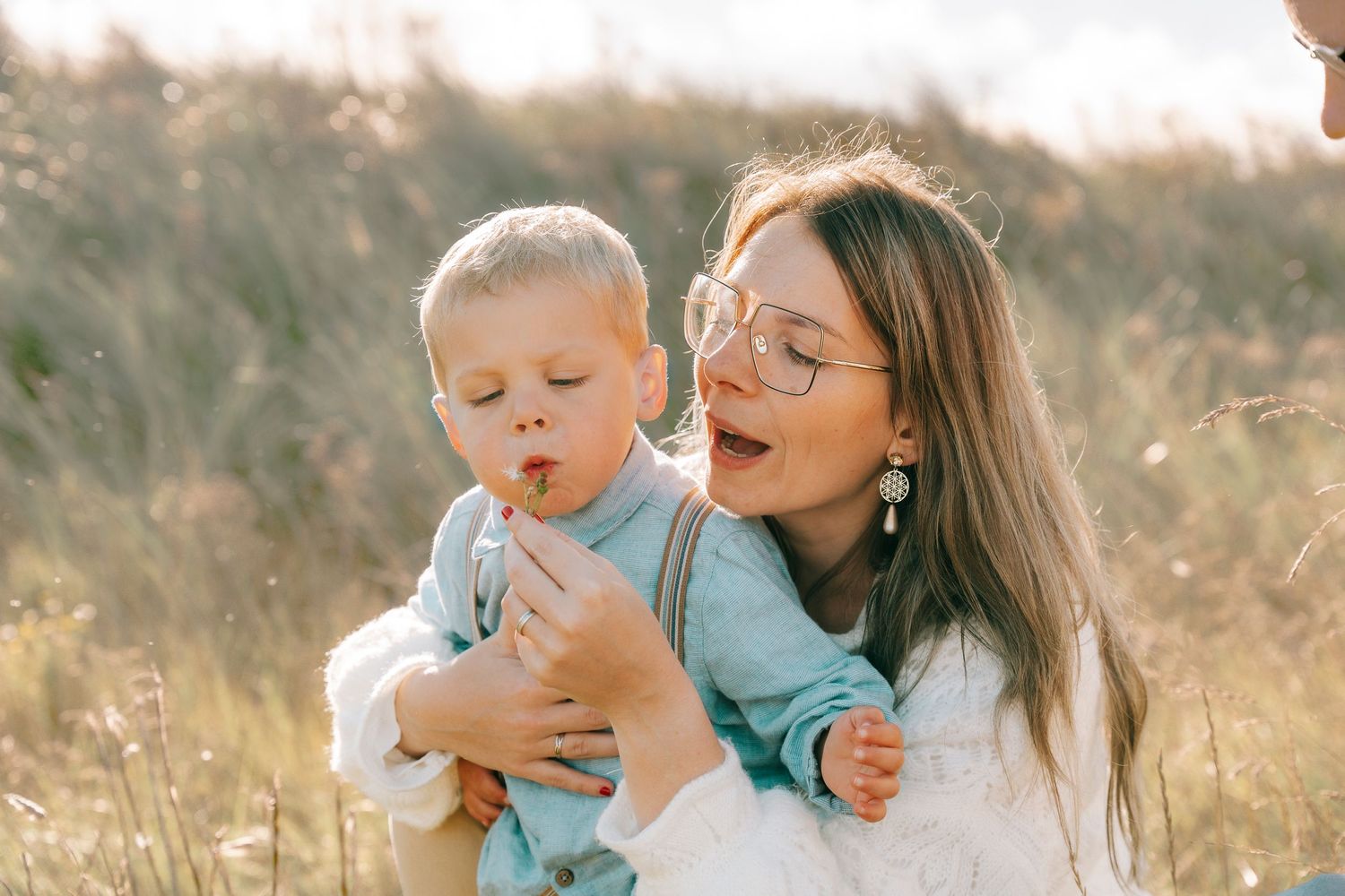 A tender moment shared between two people in a sun-drenched field of tall grass.