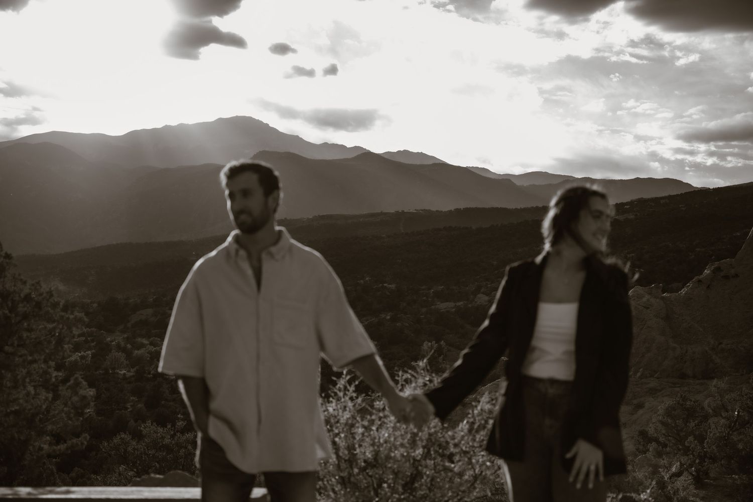 A couple sharing intimate moments against a mountainous backdrop at sunset.