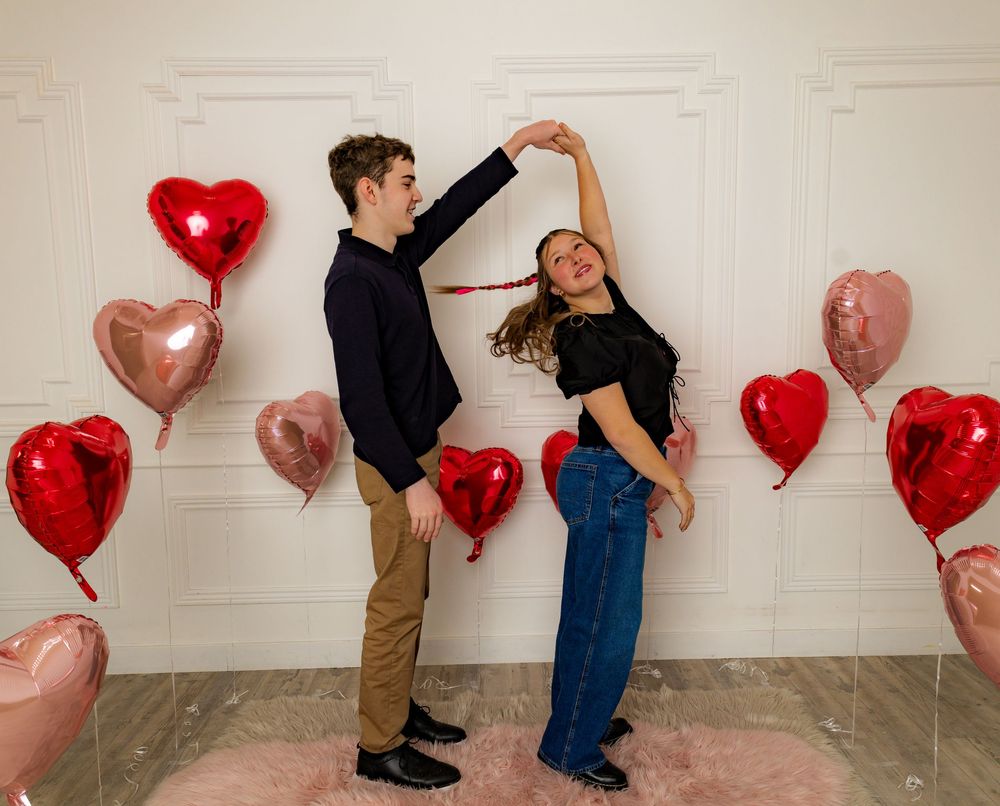 Romantic Valentine's day photo with heart balloons and dancing pose.