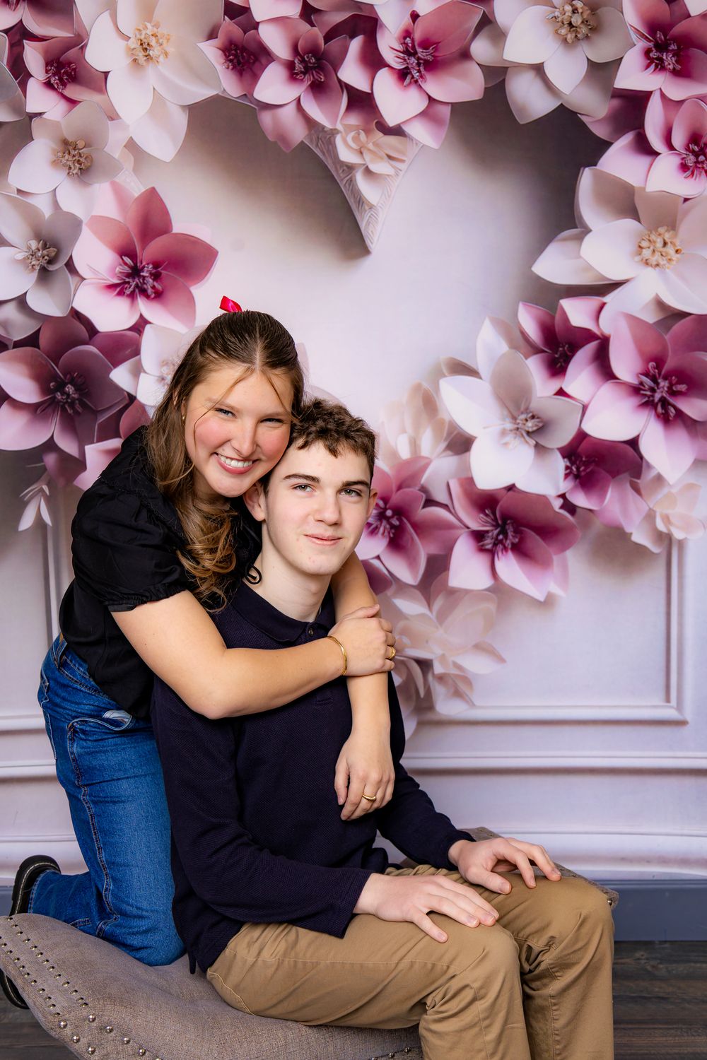 Joyful moment captured against pink floral wall decoration.