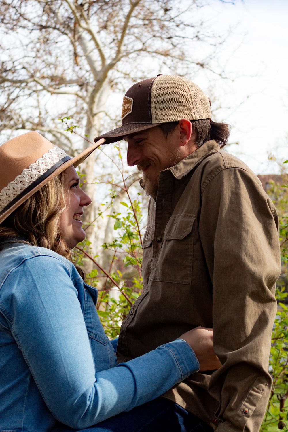 Couple sharing a tender moment while standing together outdoors near blooming trees.