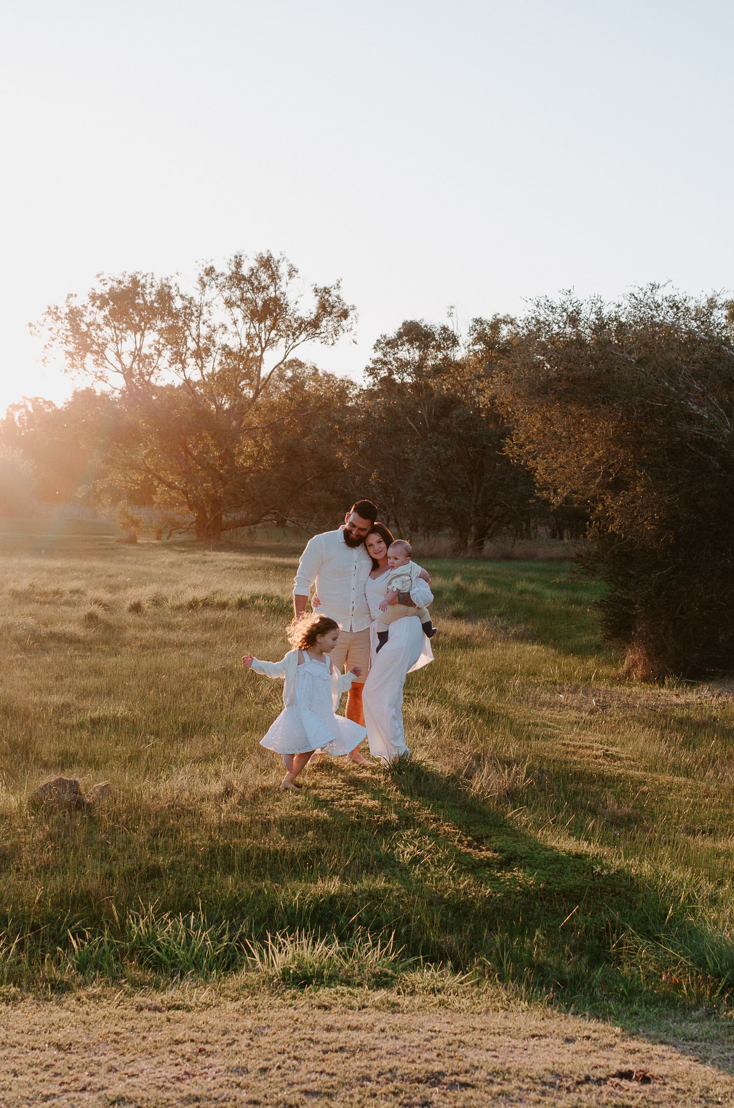 A family portrait in a field of grass, with the eldest child running rings around mum, dad and brother - Perth