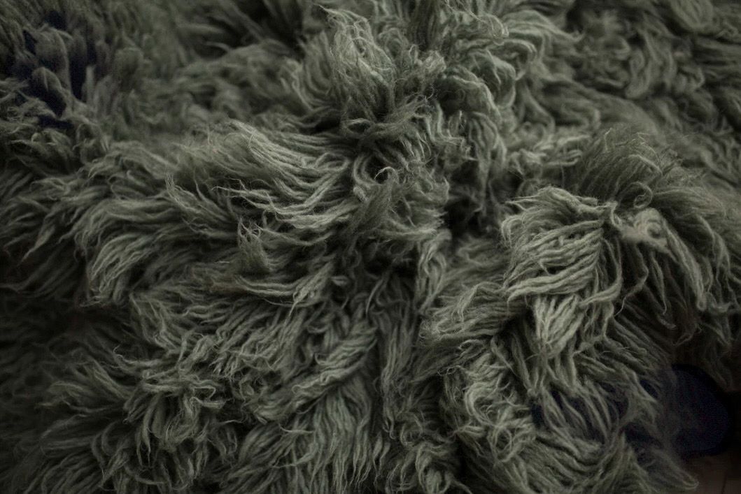 Close-up diagonal pattern of soft grey and white fur texture with wispy strands creating an abstract organic design.
