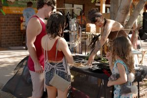 Group of people browsing items at an outdoor market or vendor stall.