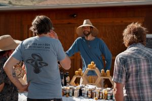 Customers browse handcrafted wooden items at outdoor market display.