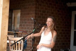 A person in white performs on an outdoor stage with a microphone setup.