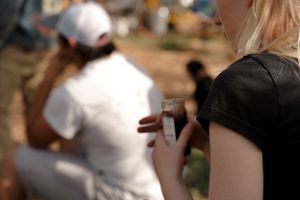 Close-up shot of someone holding a drink at an outdoor gathering.