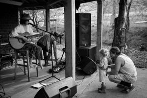 Musicians performing at an outdoor venue while children watch near the stage.