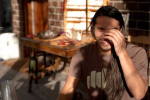 Candid moment captured indoors showing someone laughing while covering their face.