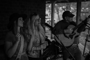 Musicians performing on stage with acoustic guitar and vocalists during a show.