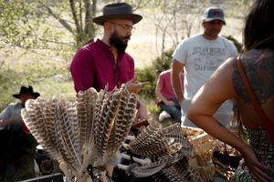 A display of decorative feathers and crafts at an outdoor market or festival.