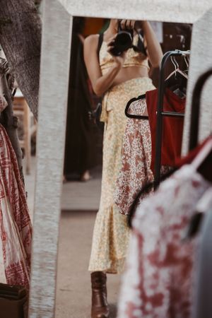Vintage-style floral dress photographed in mirror reflection at clothing display.
