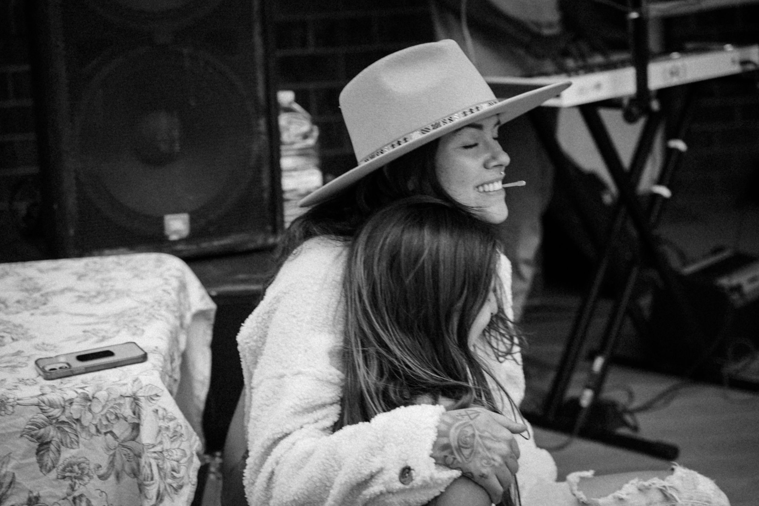 Person in a cowboy hat sitting at an outdoor music venue.