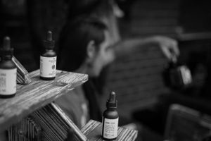 Close-up of dropper bottles arranged on a rustic wooden shelf in black and white.