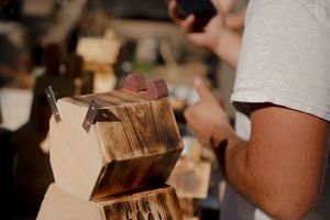 Close-up shot of hands sorting through wooden boxes at a market display.
