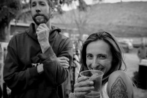 Black and white photo of two people enjoying drinks outdoors.