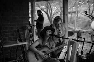 Musicians performing at an outdoor venue with acoustic guitar and equipment setup.