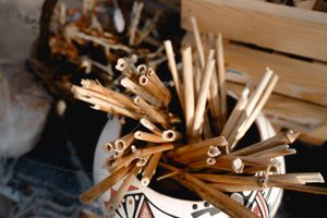 Wooden sticks and craft materials arranged in a decorative ceramic vessel.