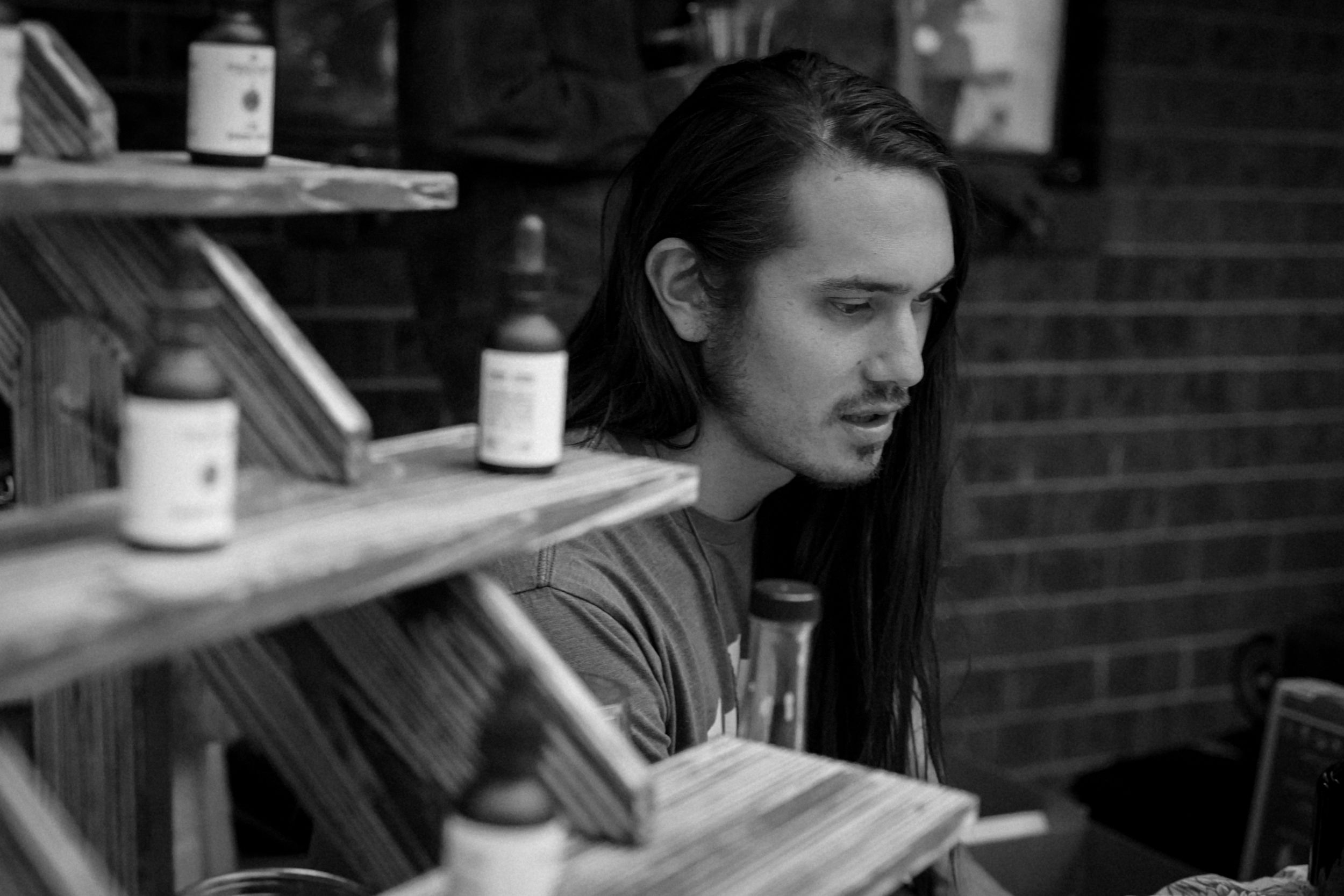 Profile view of person with long hair examining items on wooden shelving.