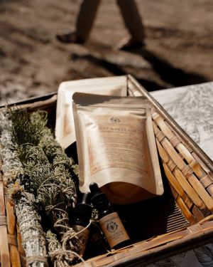 Wicker basket filled with herbal bundles, pouches and natural wellness products in warm sunlight.