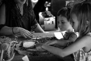 Children examine decorative crafts and jewelry on a table during an outdoor event.