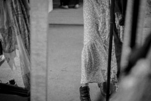 Black and white image showing lower portion of vintage-style dress and boots.