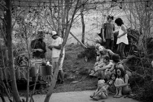 Black and white photo of gathering in wooded outdoor setting.
