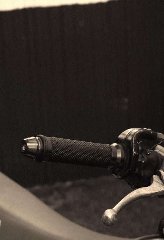 Close-up view of black motorcycle handlebars and controls in monochromatic style.