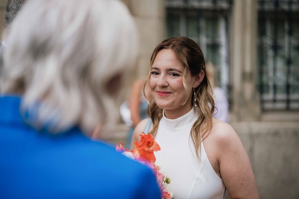 Joyful conversation between wedding guests with vibrant coral flowers.