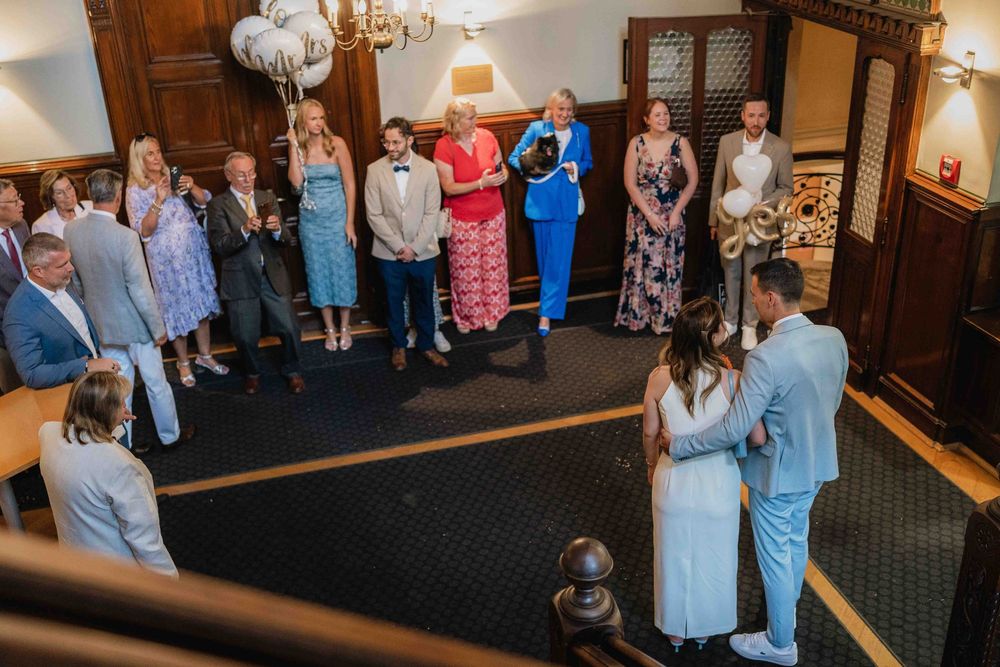 Wedding celebration gathering in elegant wood-paneled room with chandelier.