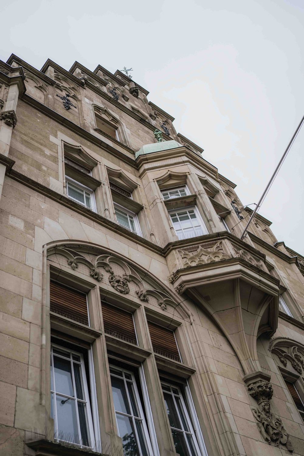 Detailed view of stone carved architectural features and windows on a Gothic style building facade.