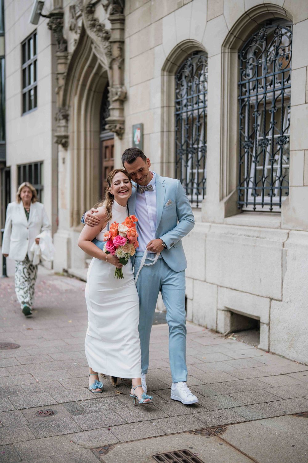 A couple celebrates their special moment walking together outside a historic building.