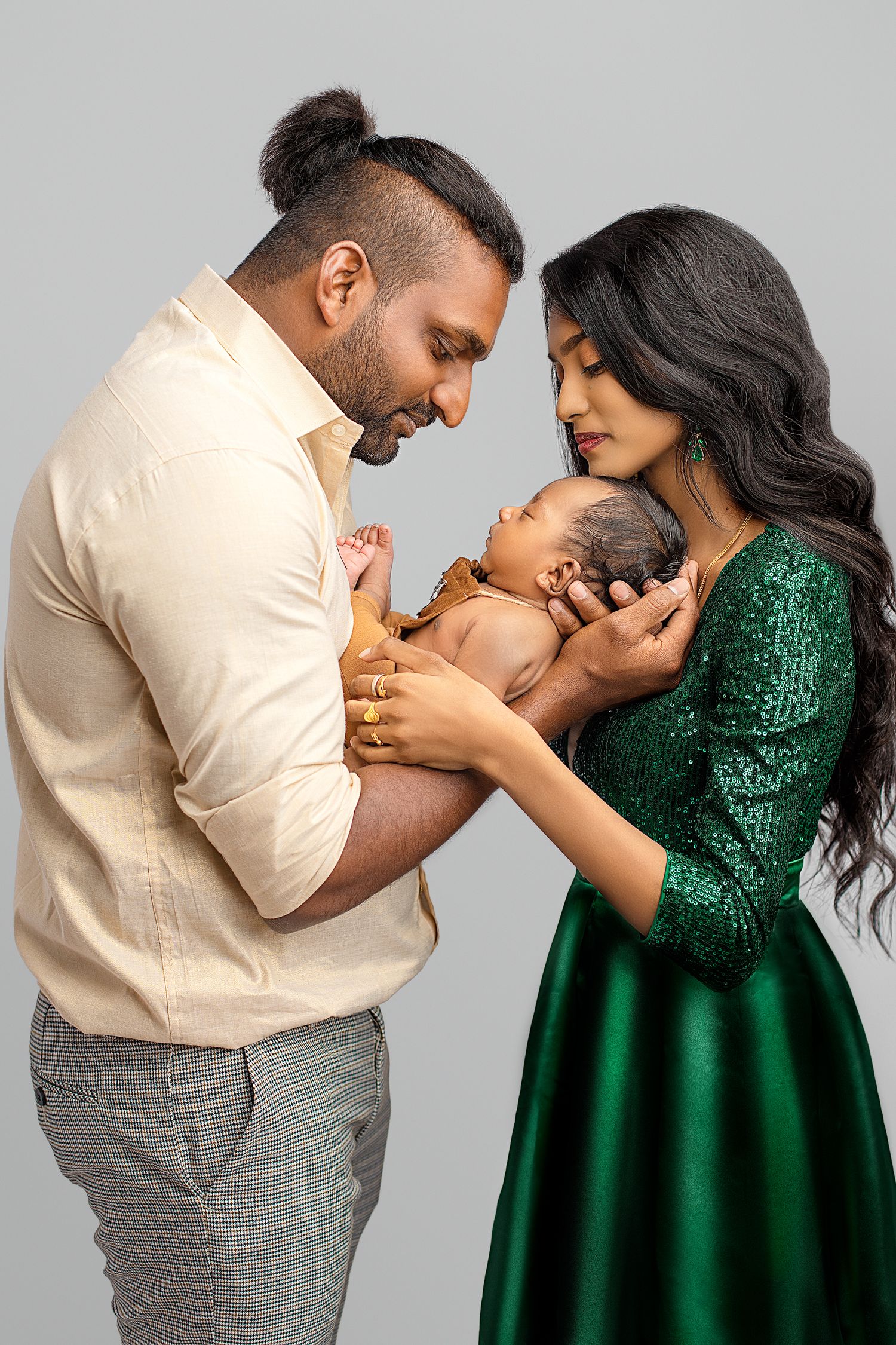 A romantic couple in matching formal attire share intimate moments, with the woman wearing a sparkly emerald green dress. south indian famil