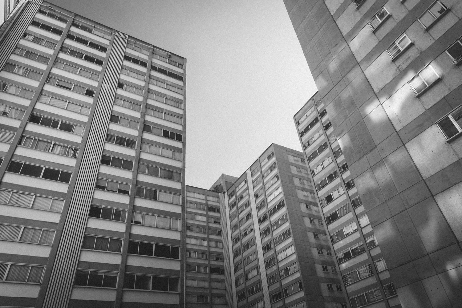 Low angle view of brutalist concrete apartment buildings against an overcast sky.