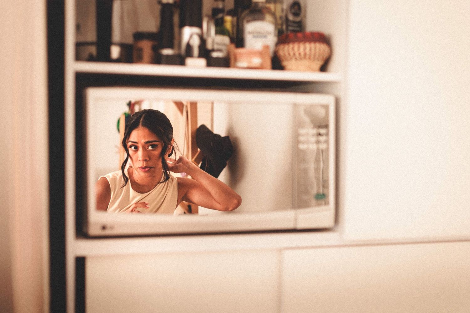 A mirror reflection shows someone styling their hair in warm lighting.