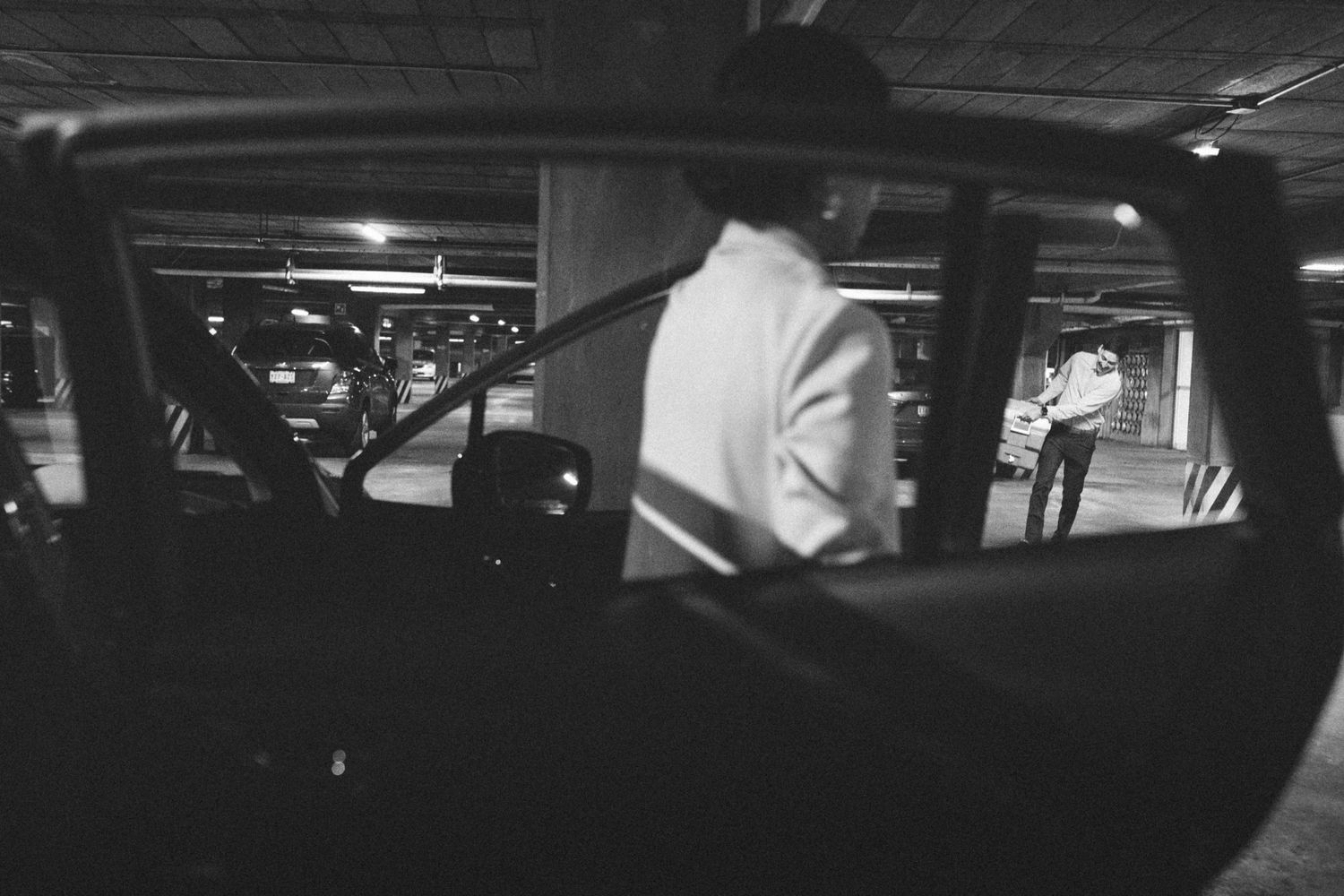 Black and white image of silhouettes in a dimly lit parking garage.