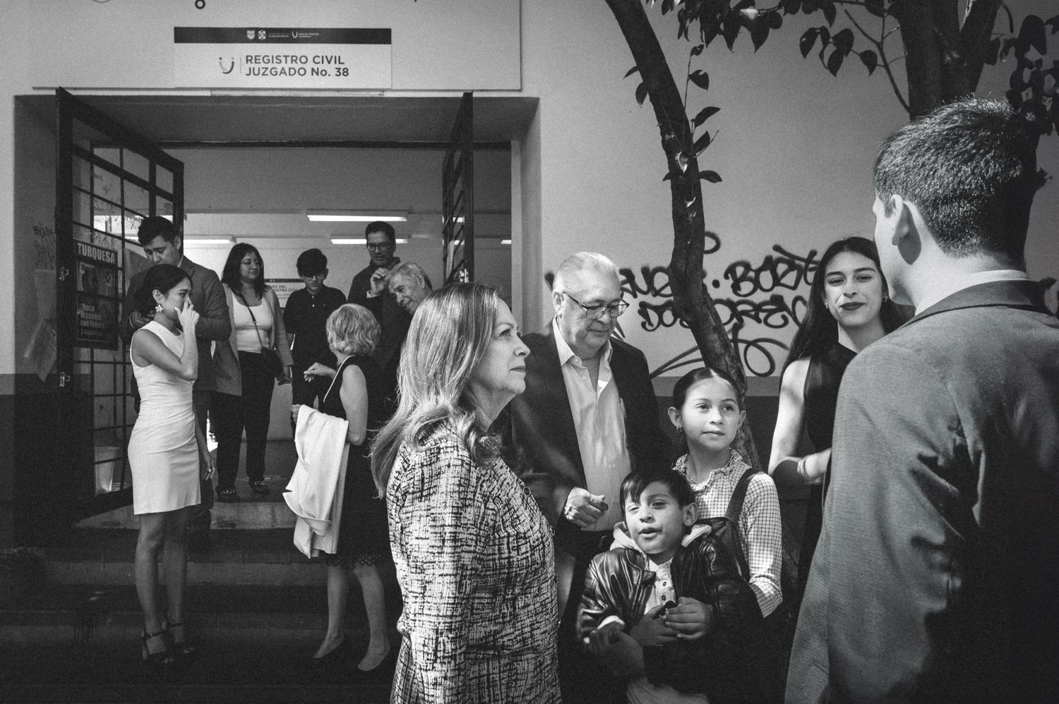 Candid black and white photo of people gathered in a school hallway.